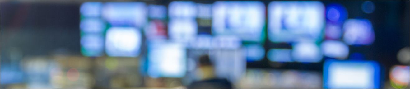 Blurry image of a person studying a bank of monitors