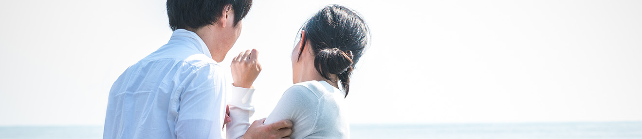 A man grabs a woman near the ocean.